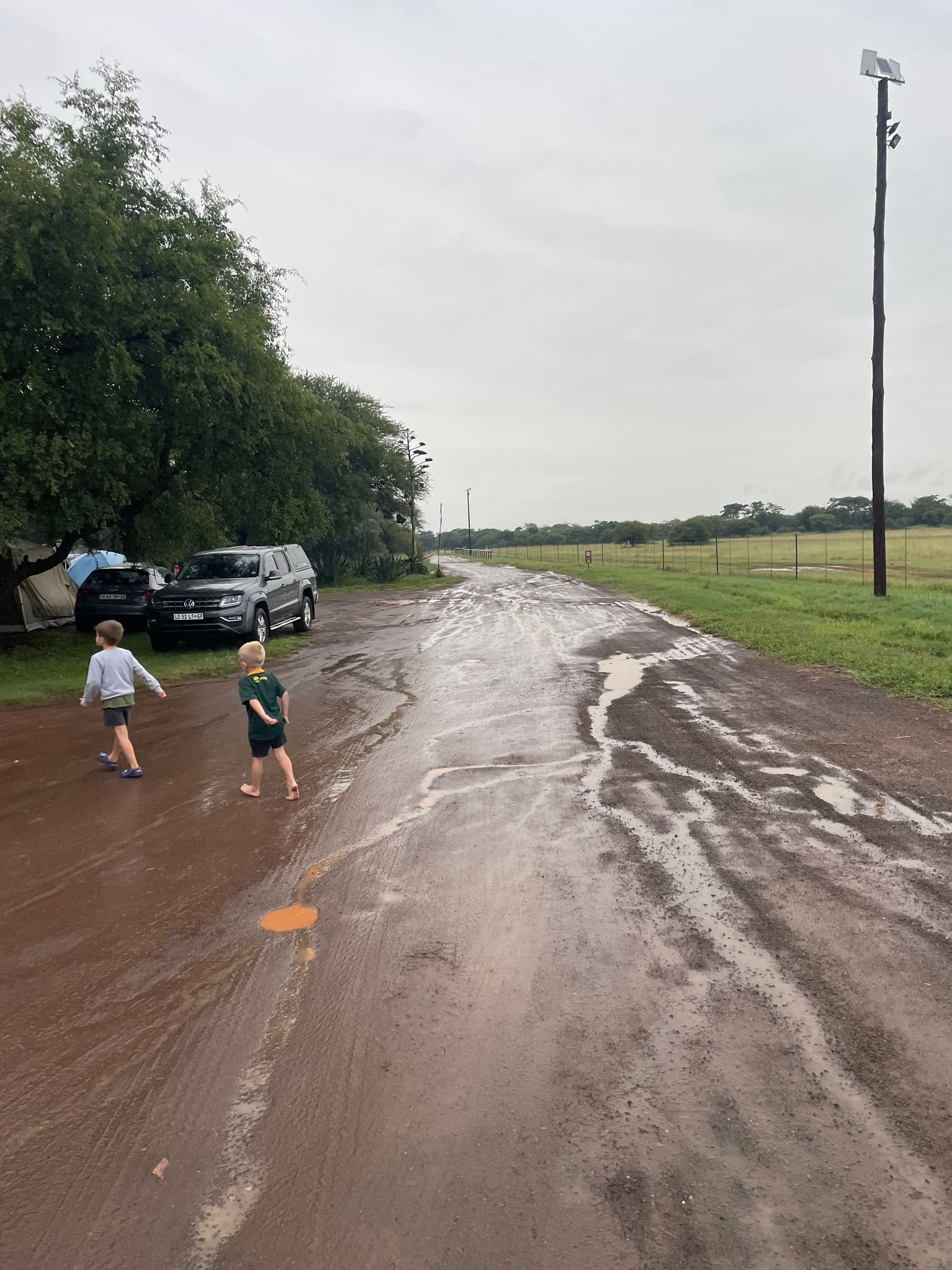 Kids playing in a puddle on the muddy road at the Sondela, Bela Bela campsite after rain