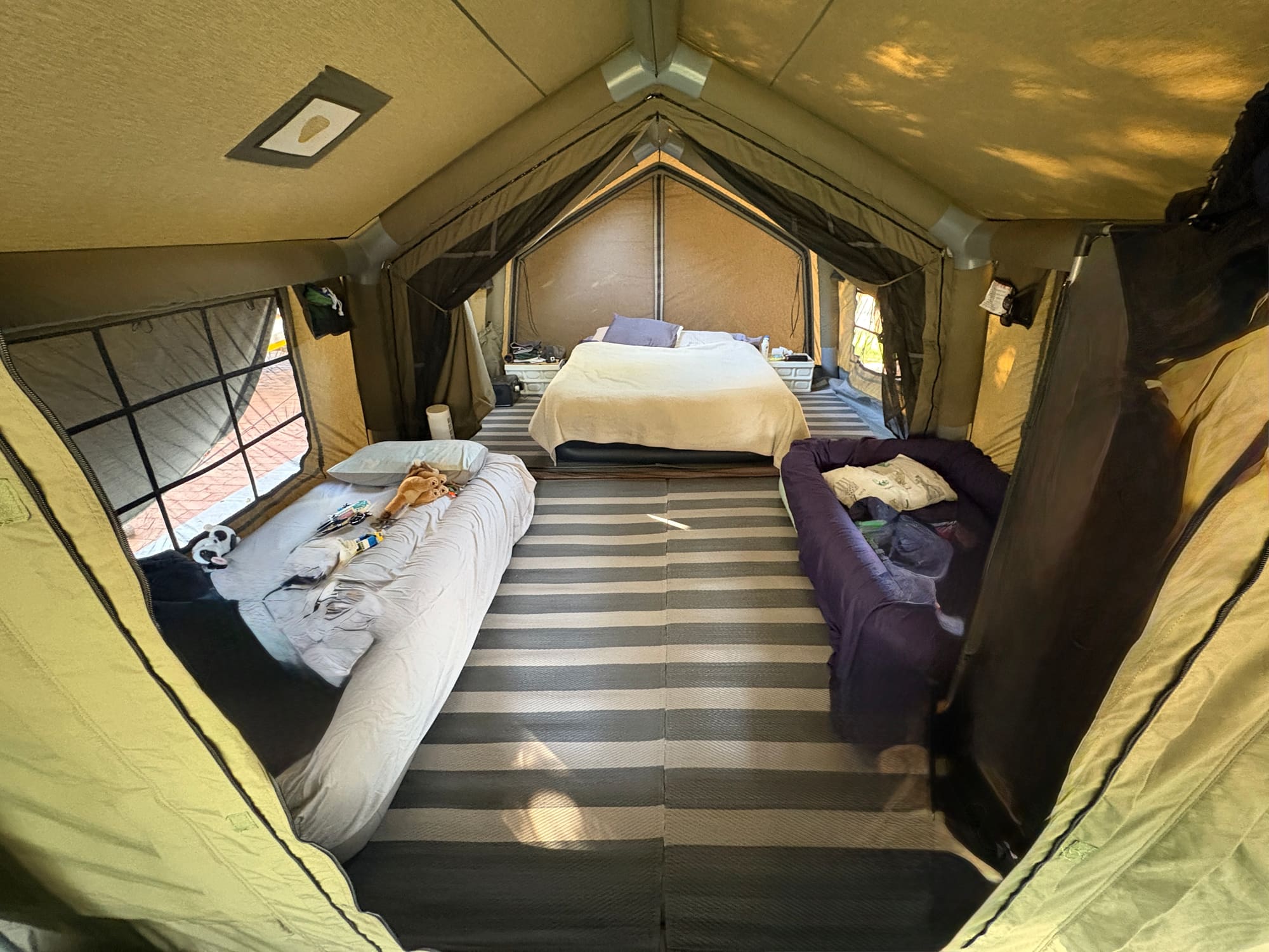 Interior of the Coody Familia tent showing a double bed, single mattress, and a cot set up for the family to sleep