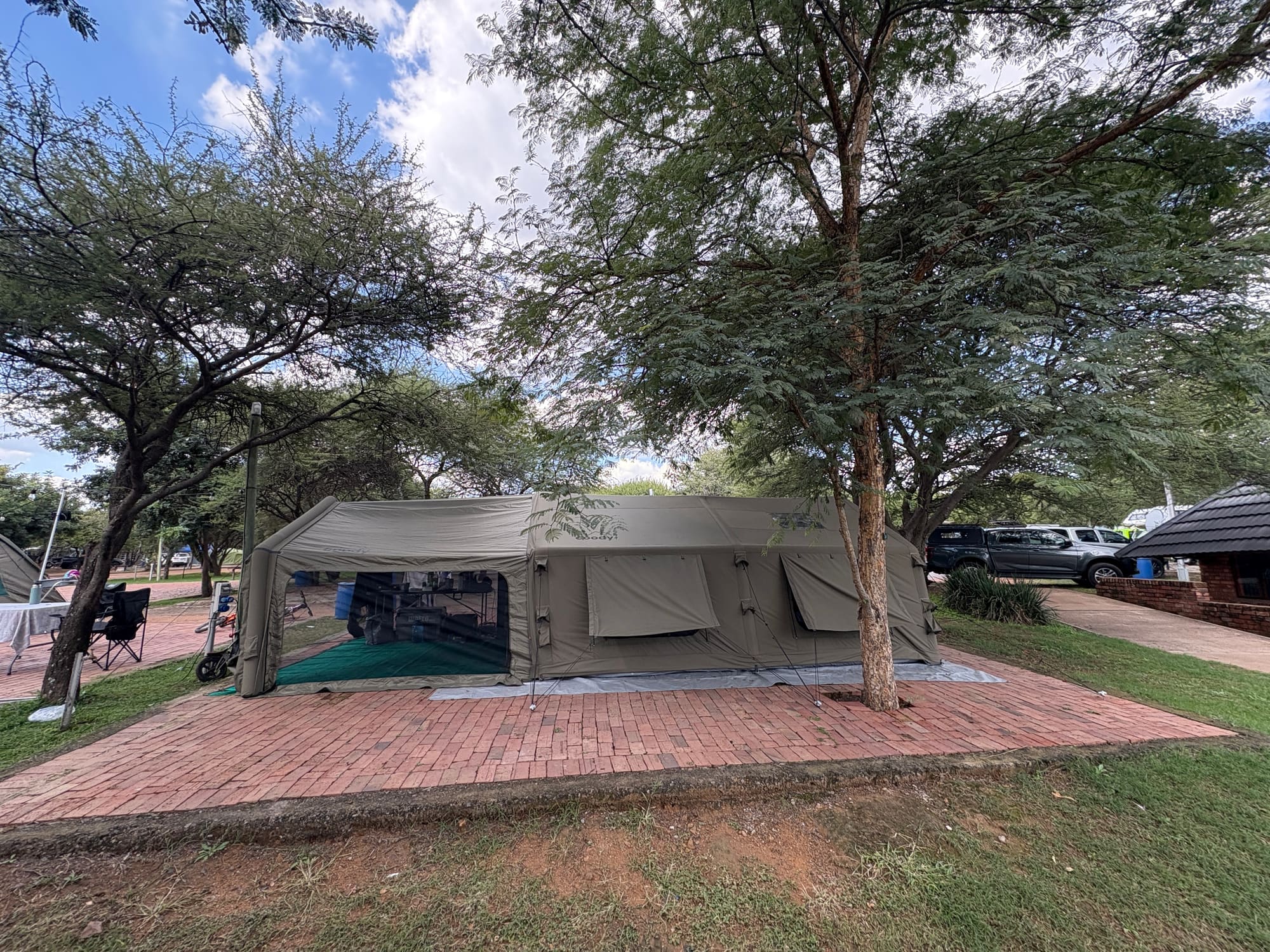 Coody Familia inflatable tent set up under large trees at Dube, Brits