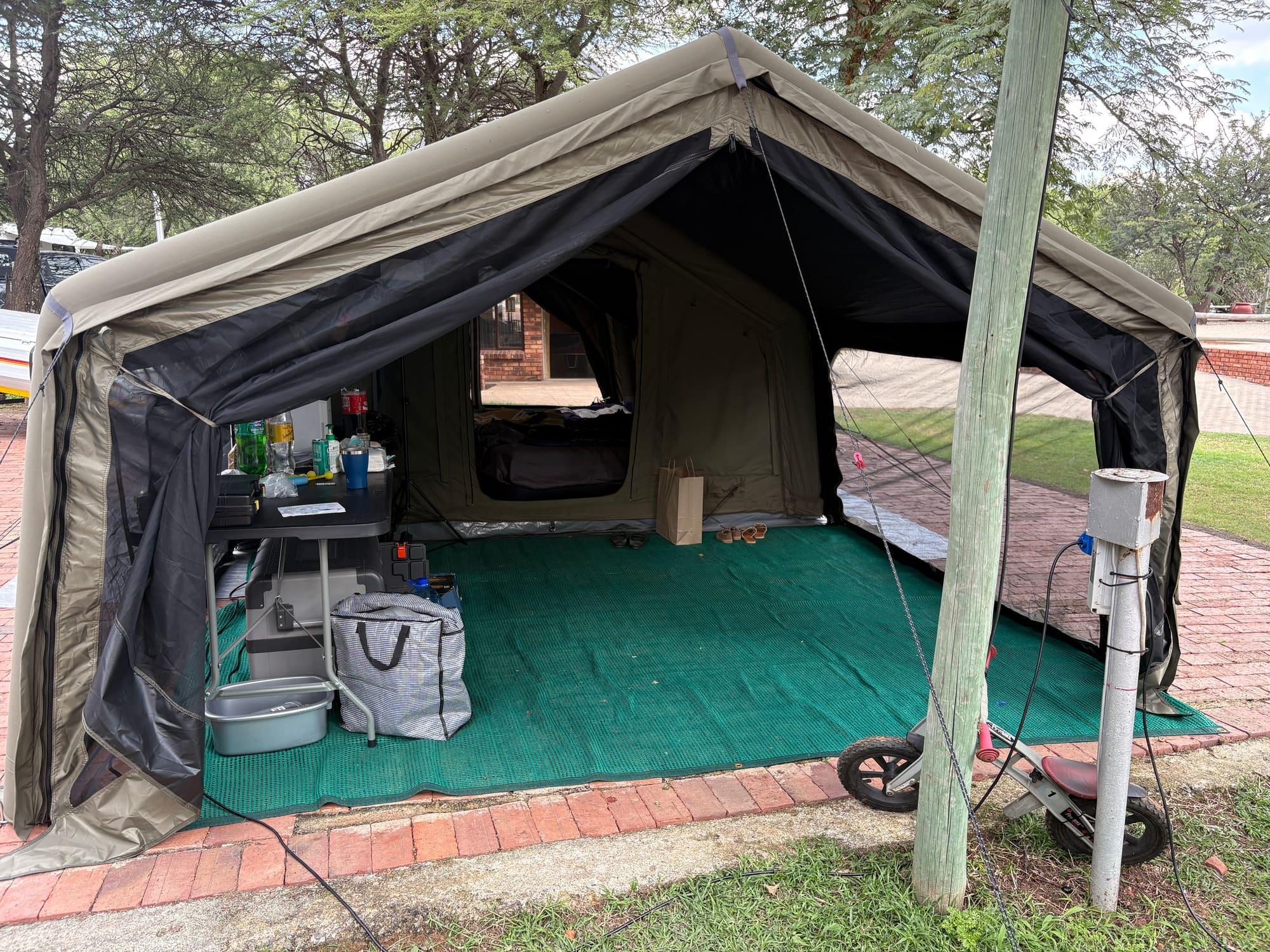 Open annex area of the Coody Familia tent set up as an outdoor living space with table and camping gear
