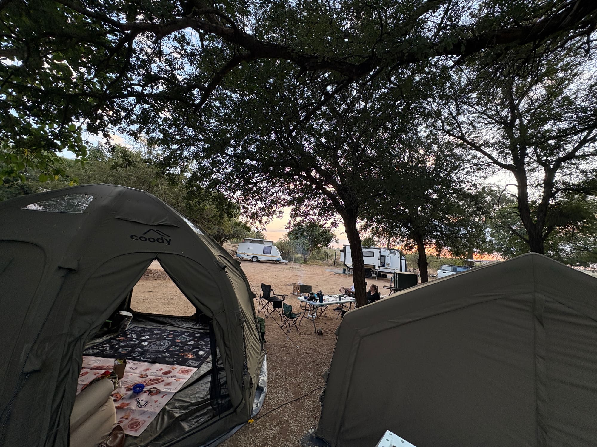 View from inside the Coody dome tent at dusk, looking out at the Familia tent and campfire at Crocodile Bridge