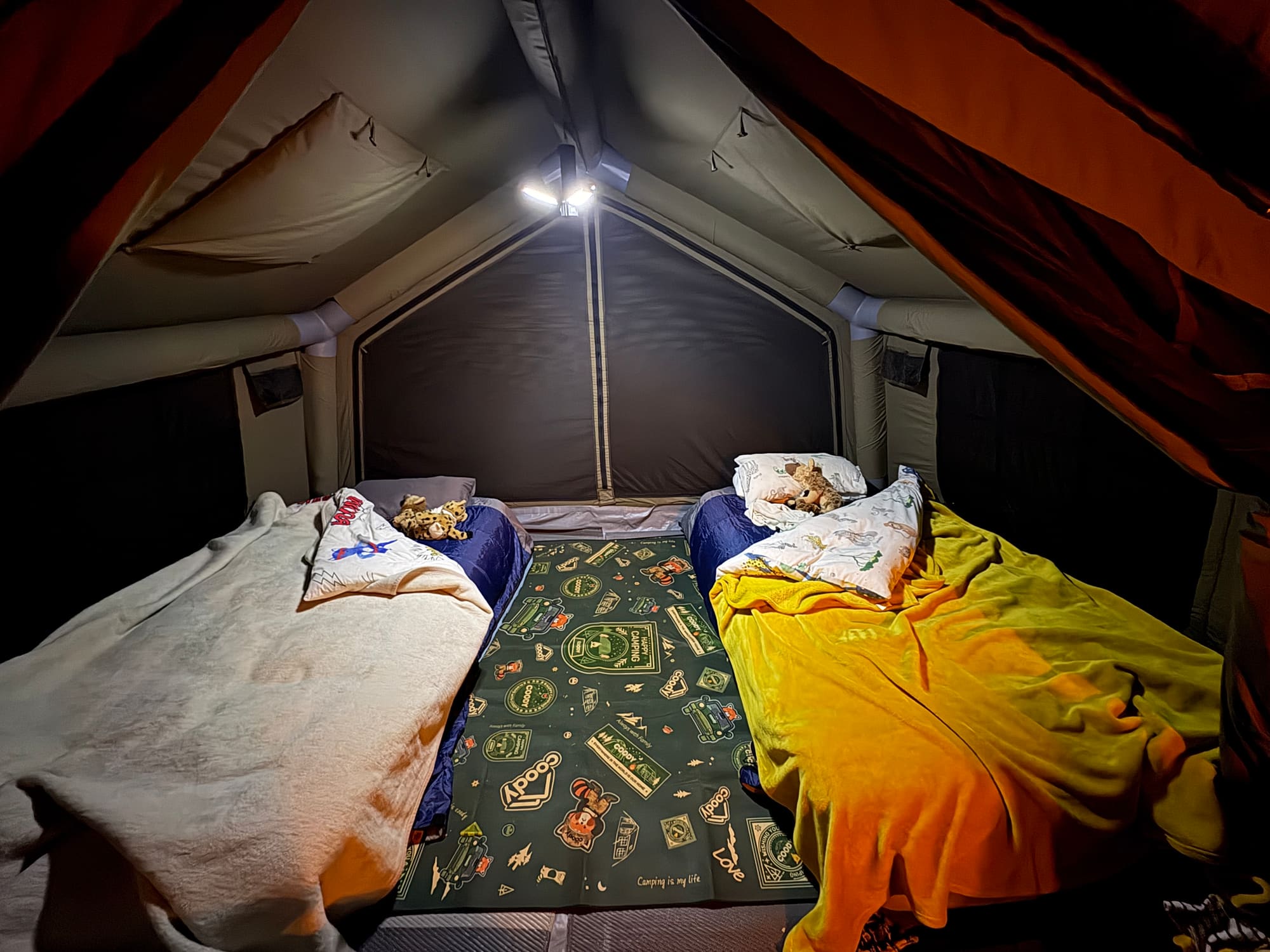 Two kids' beds made up inside a Coody Familia tent at night on the Coody-branded groundsheet