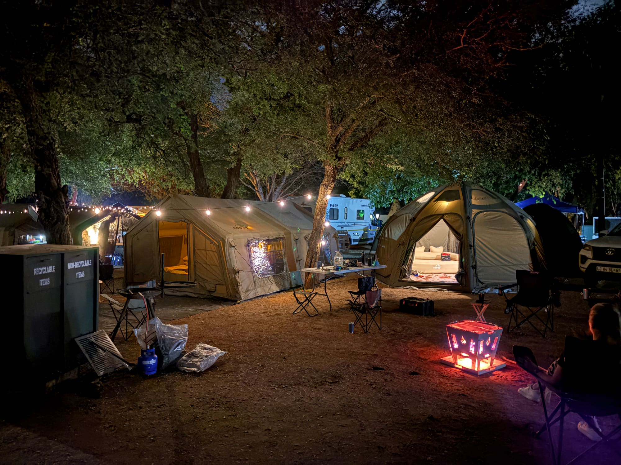 Coody Familia and dome tents lit up at night at Crocodile Bridge, fire pit glowing