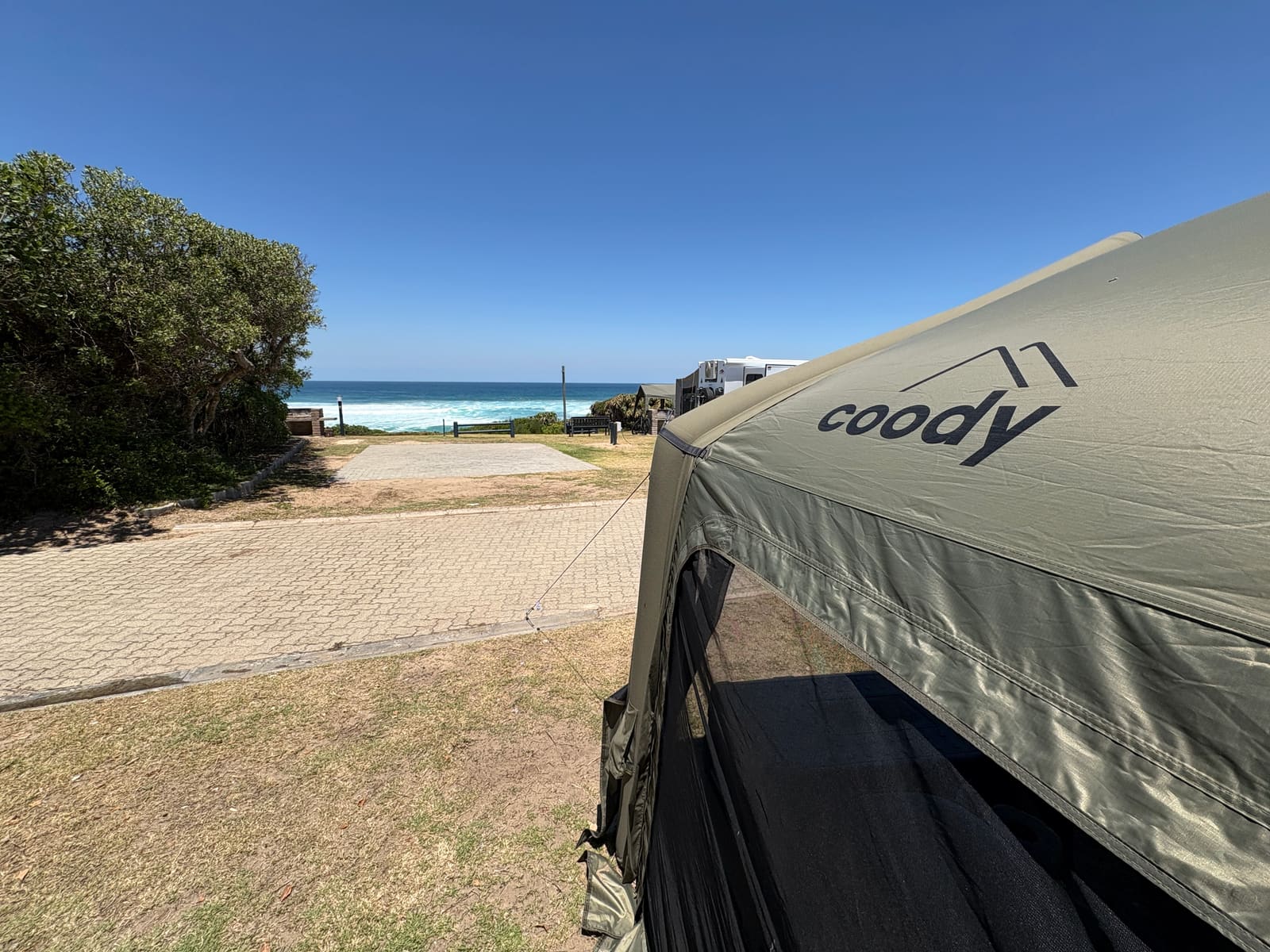 Coody branding on the tent awning with the ocean visible behind