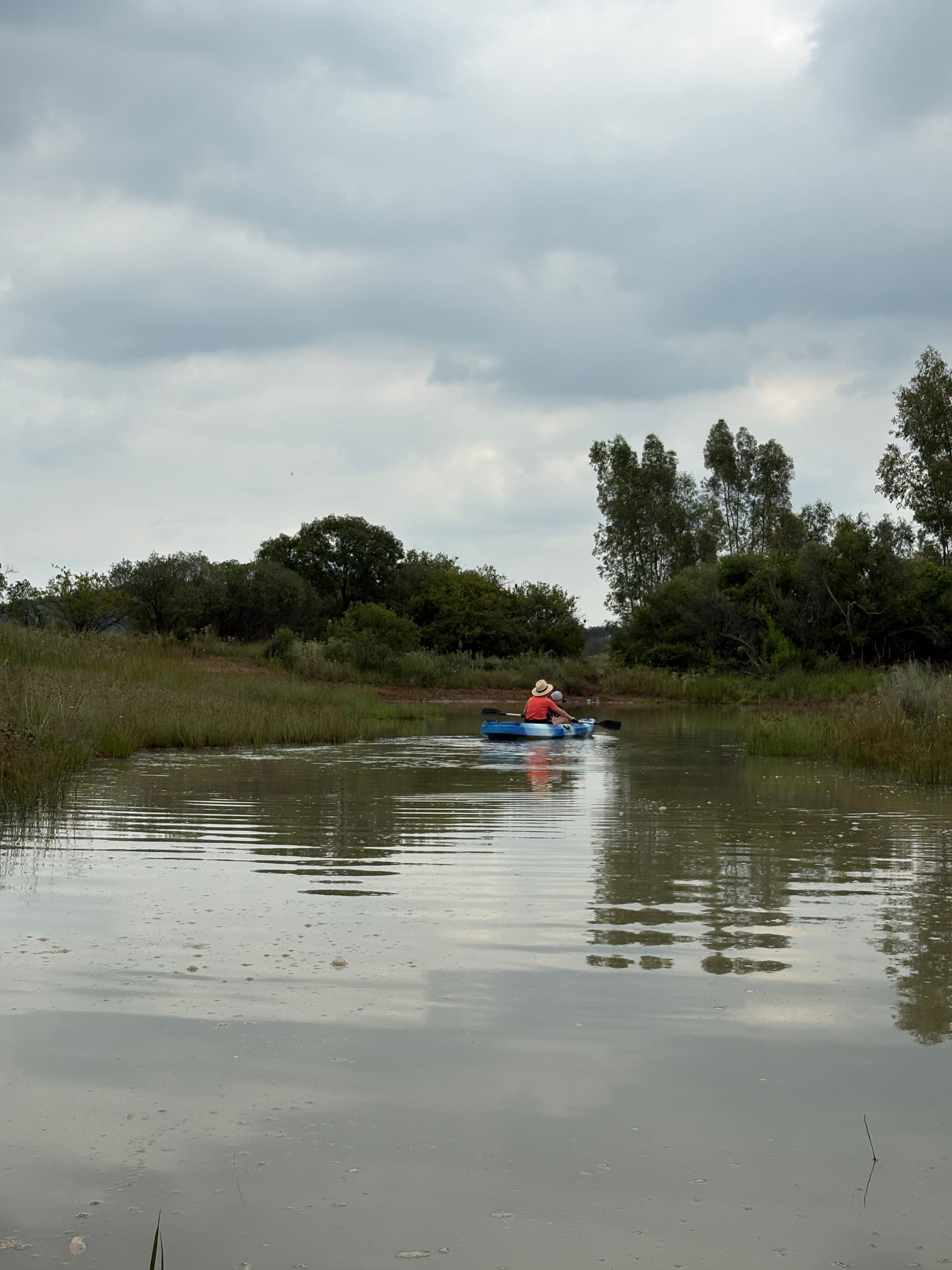 A dad and child paddling a kayak on the dam at sunset at Kleinood