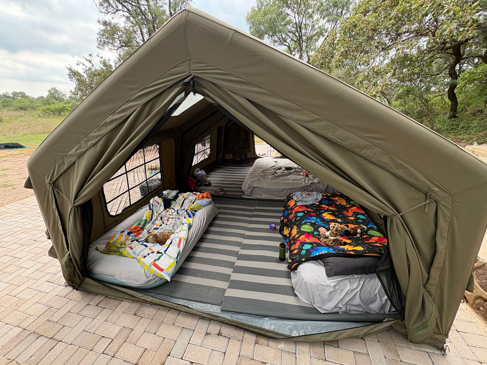 Interior of the Coody tent at Kleinood with two kids' beds made up, toys scattered on the mats