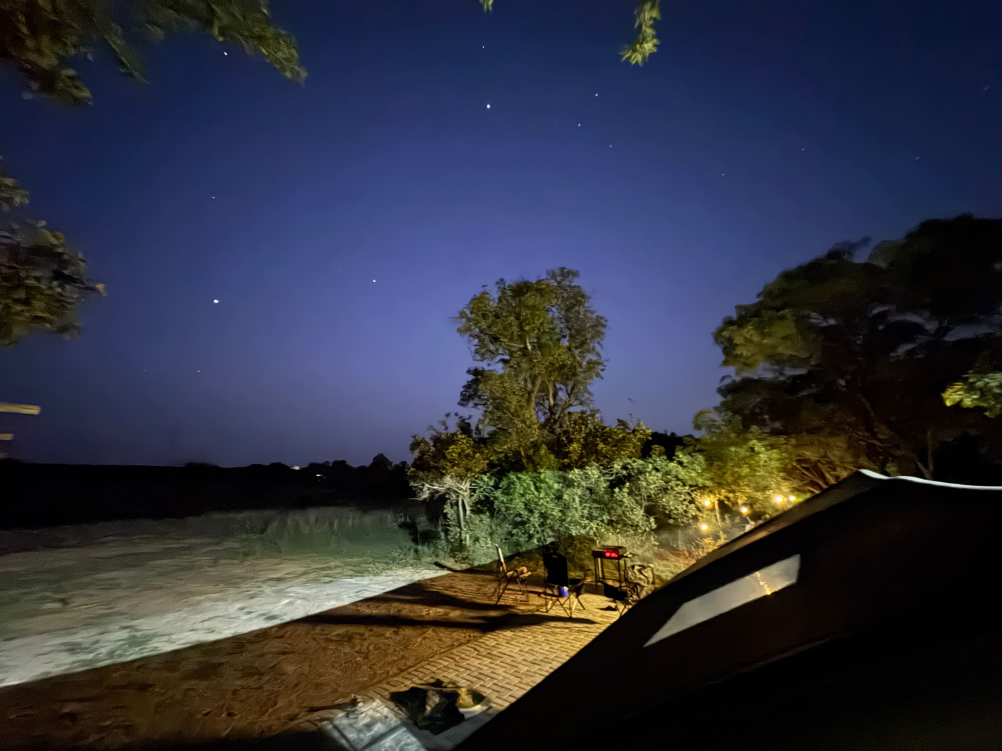 Coody tent roof at night with the vent flap open, pergola building visible behind