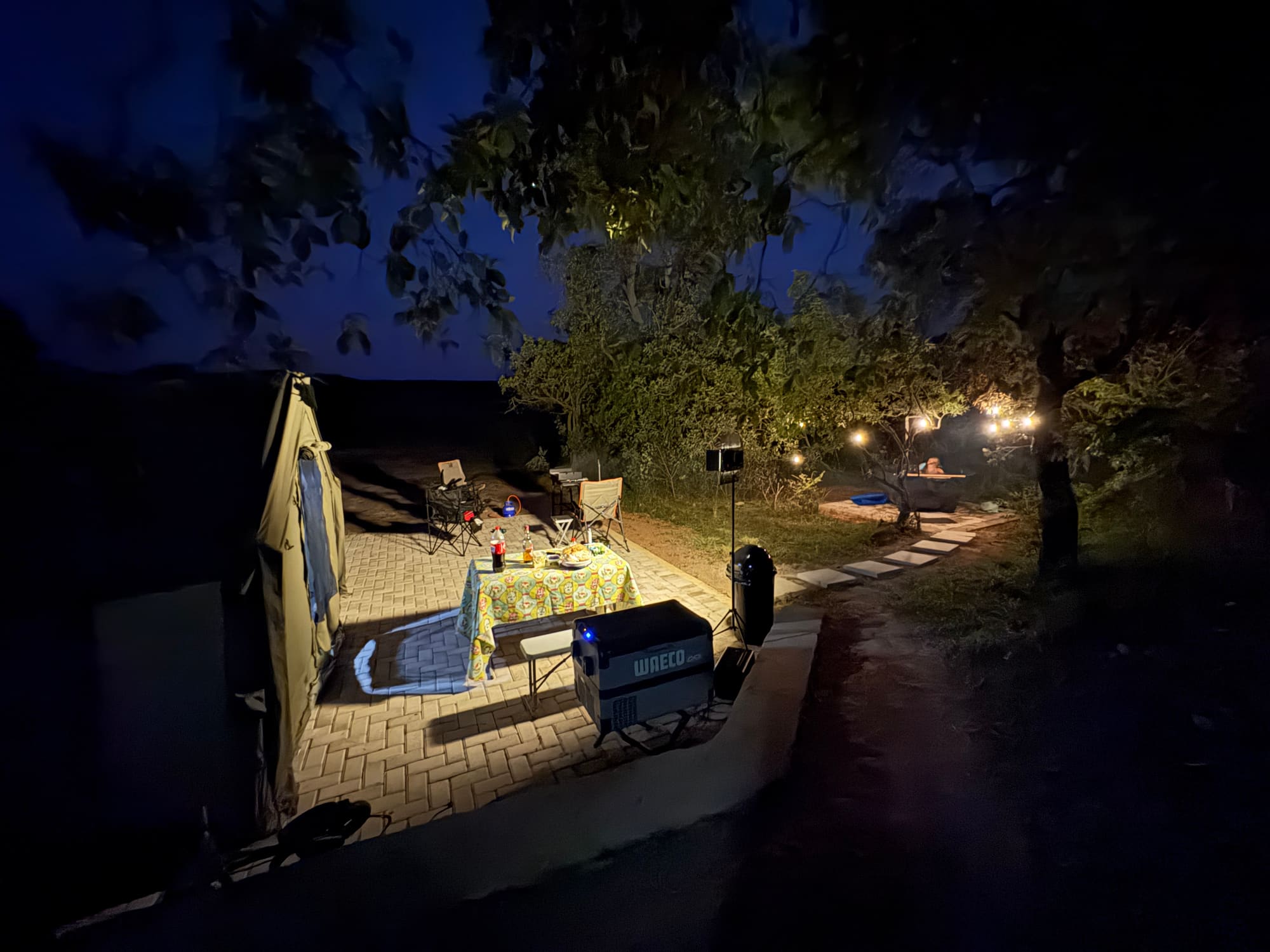 Coody tent at night lit by an overhead porch light