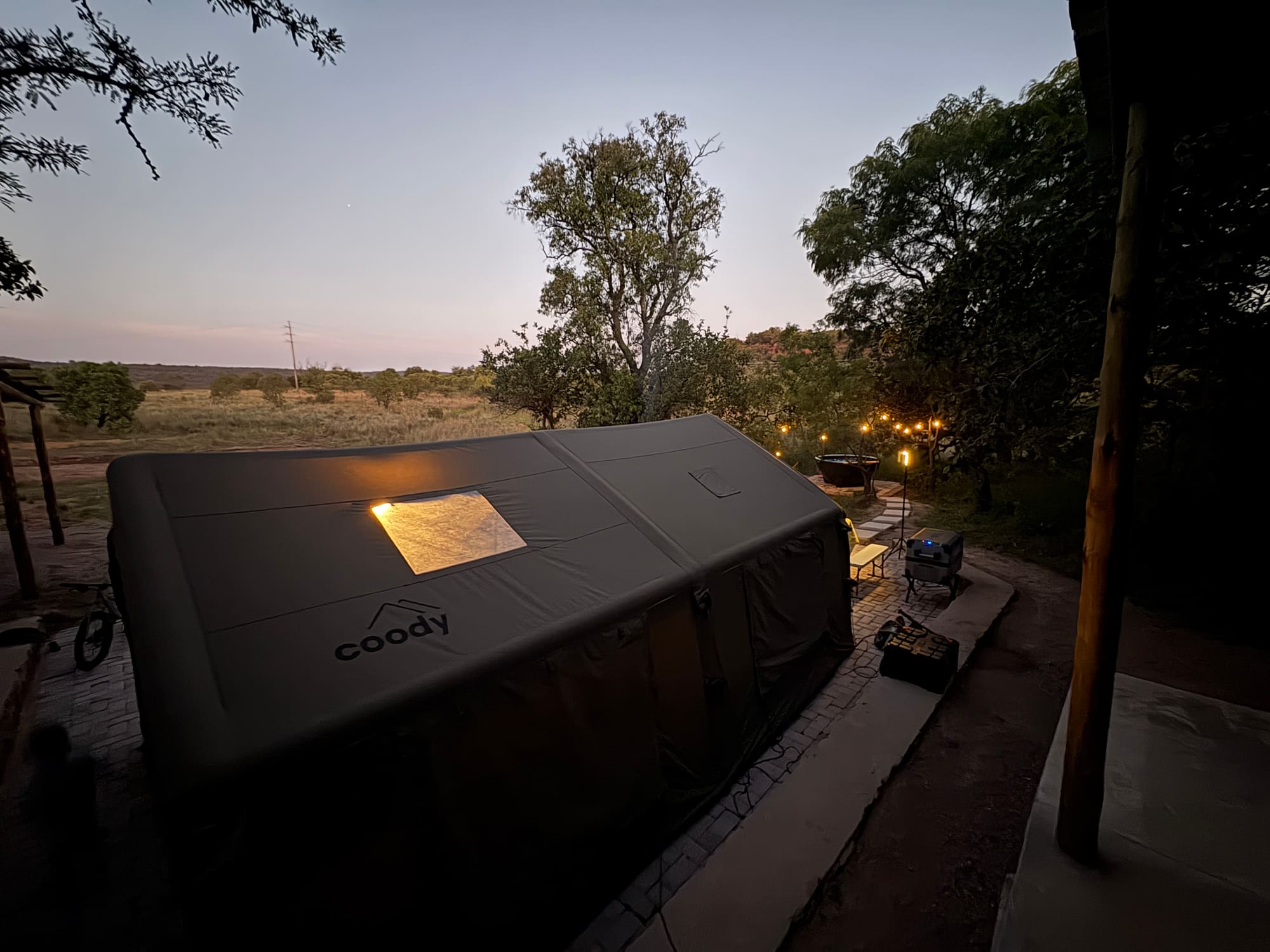 Close view of the Coody tent gable at night with a bed visible through the window
