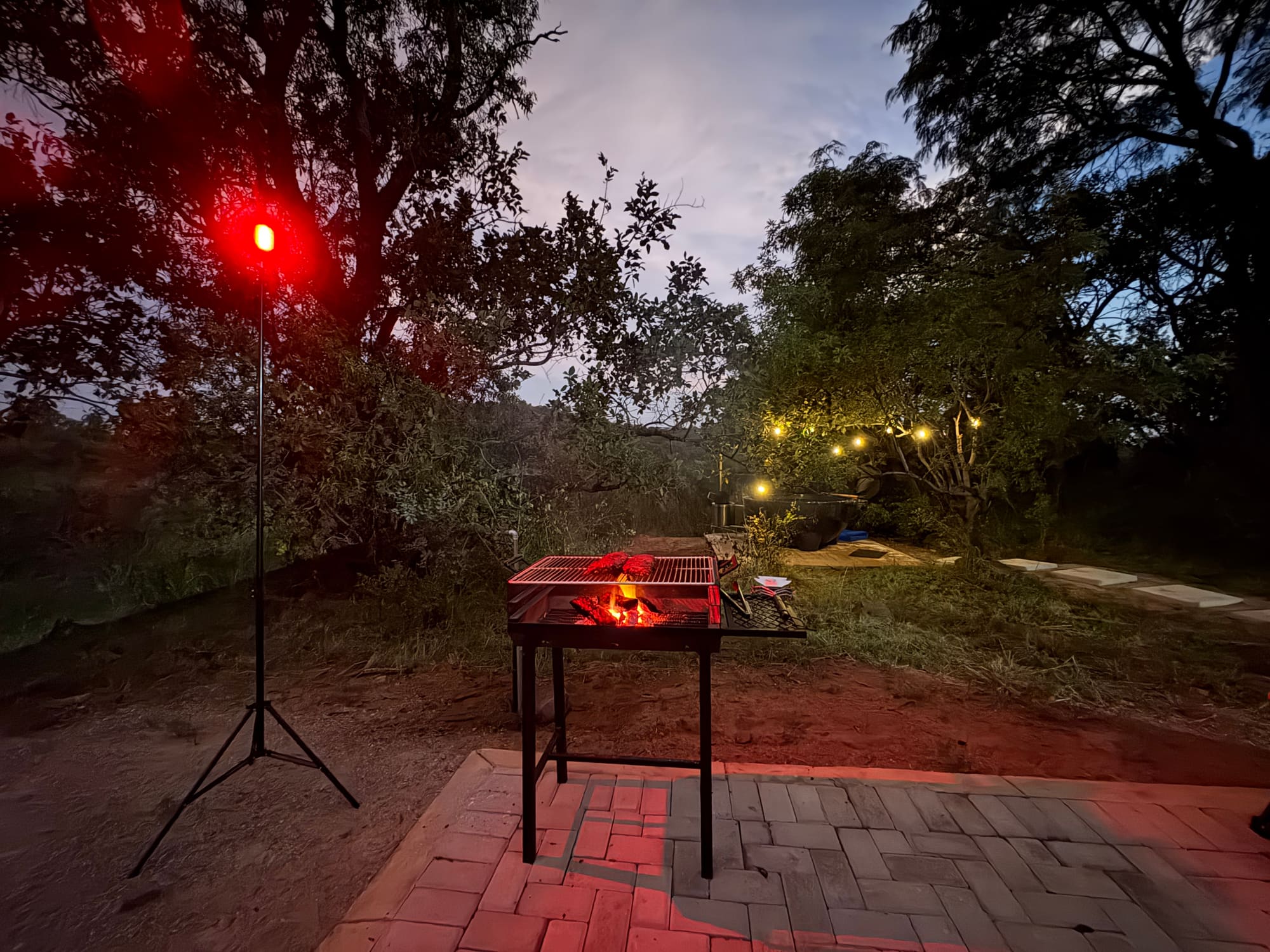 Braai fire glowing at night at Kleinood, string lights and hot tub visible in the background