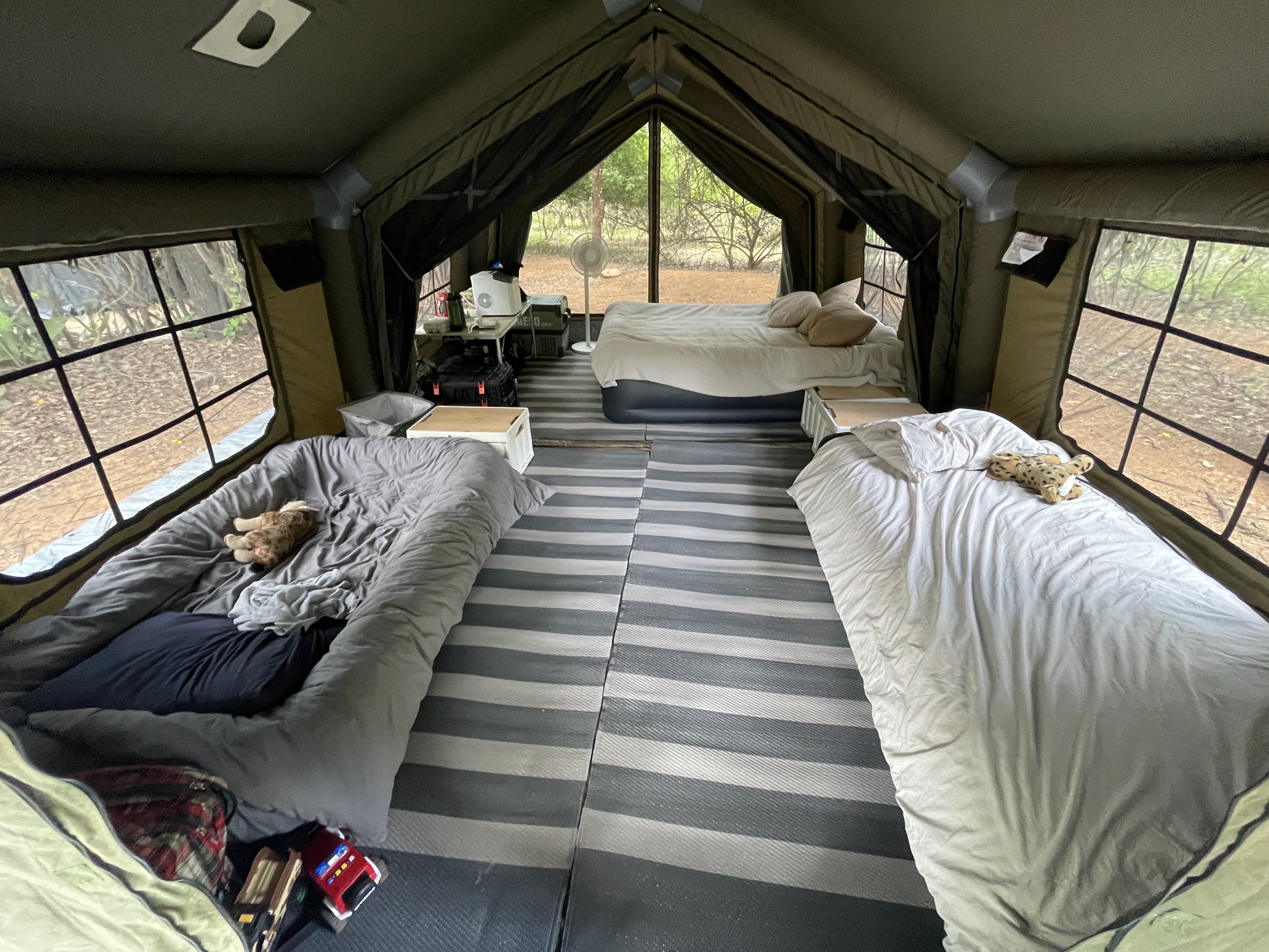 Four sleeping beds set up inside the Coody Familia tent — two parents, two kids, all the gear
