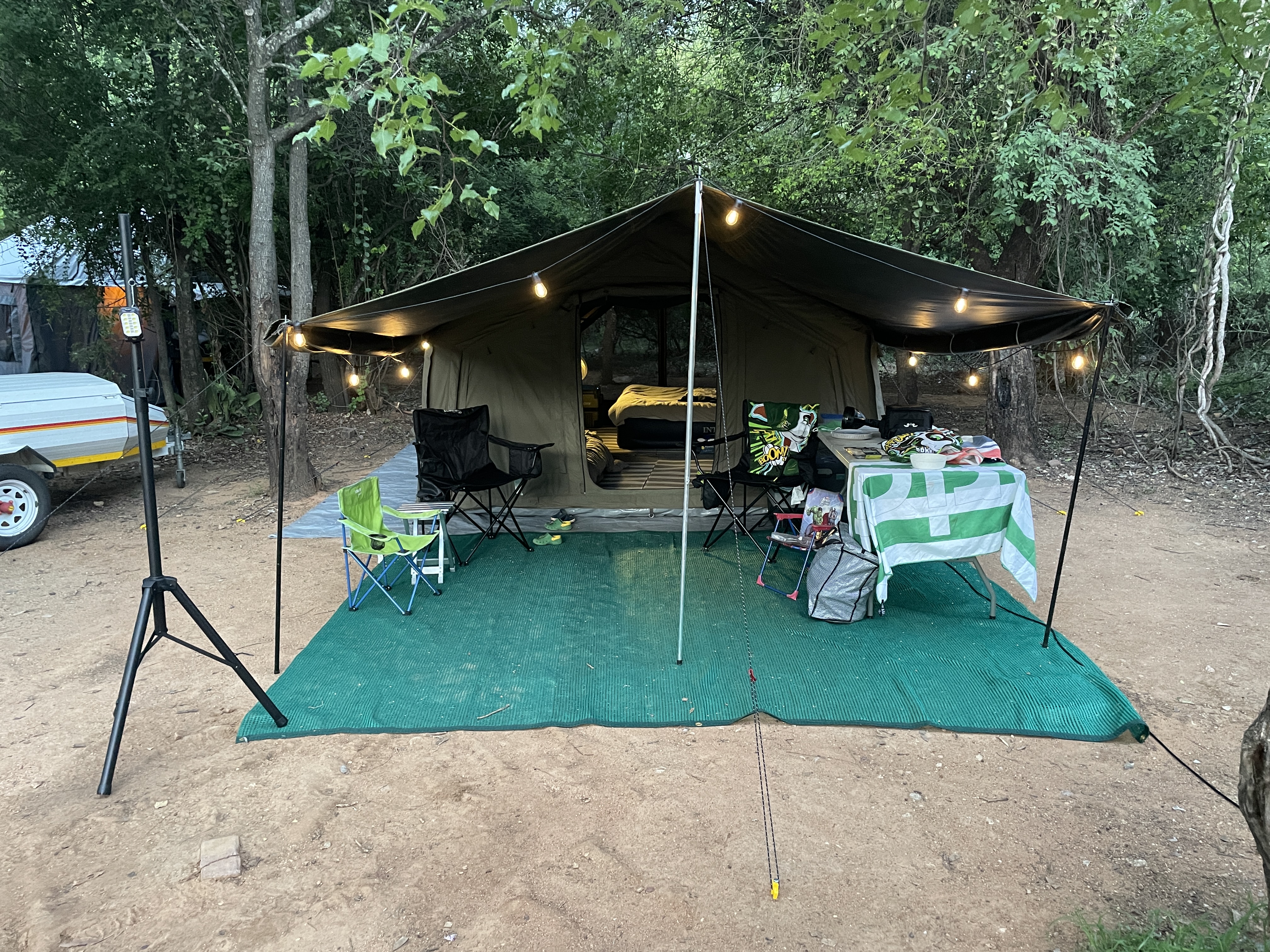 Coody Familia tent at dusk with rain fly extended as a stoep, string lights glowing, table set underneath