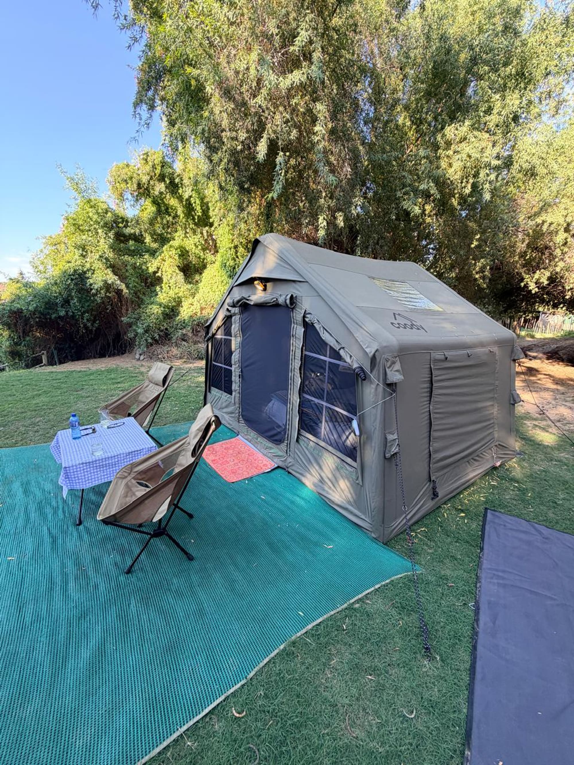 Coody 8 inflatable tent set up under willow trees on the banks of the Orange River