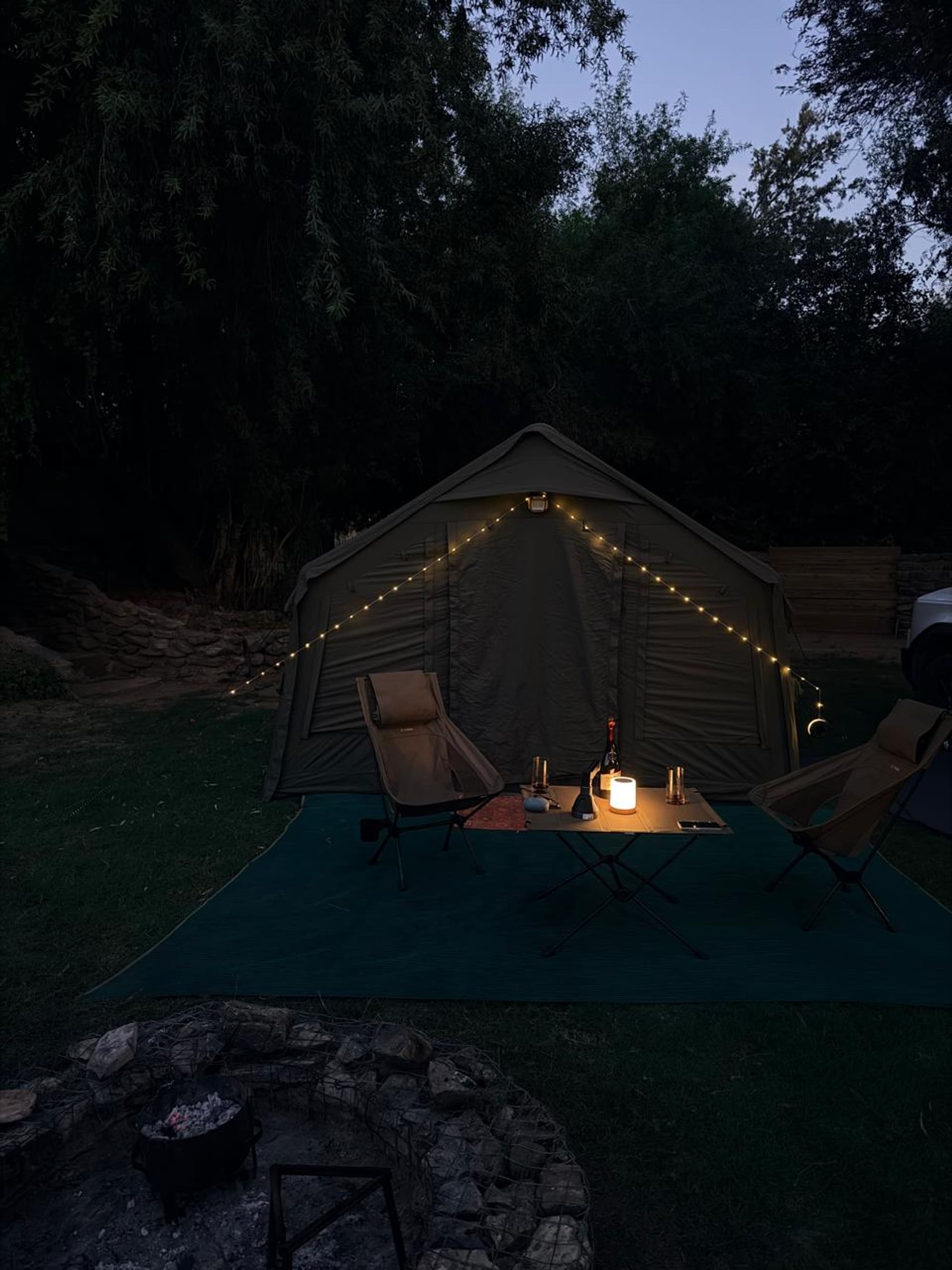 Coody 8 tent at dusk on the Orange River, string lights glowing, fire pit in the foreground