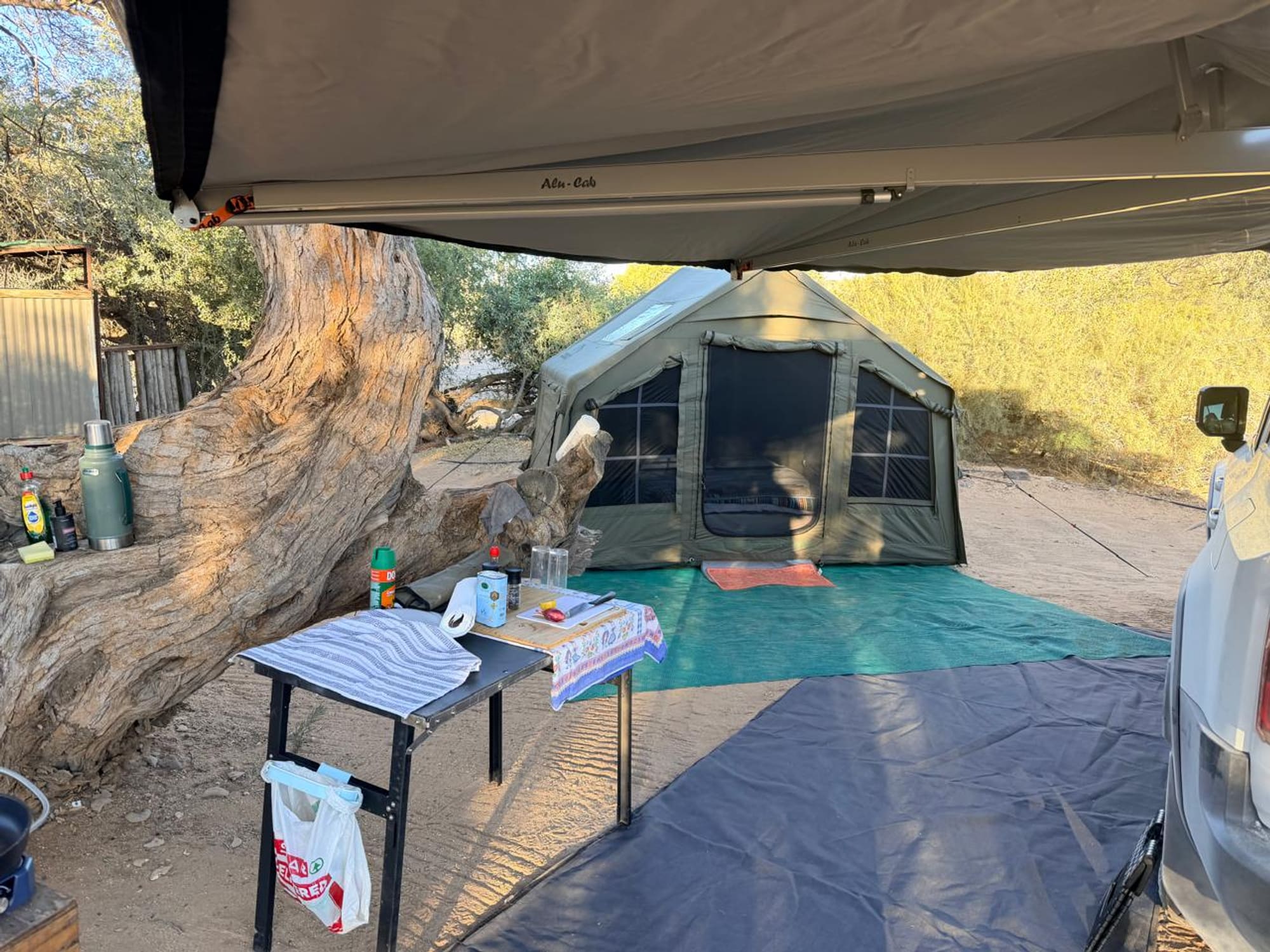 Coody 8 tent pitched at Spitzkoppe, Namibia, under a vehicle awning with a camp kitchen table set up alongside