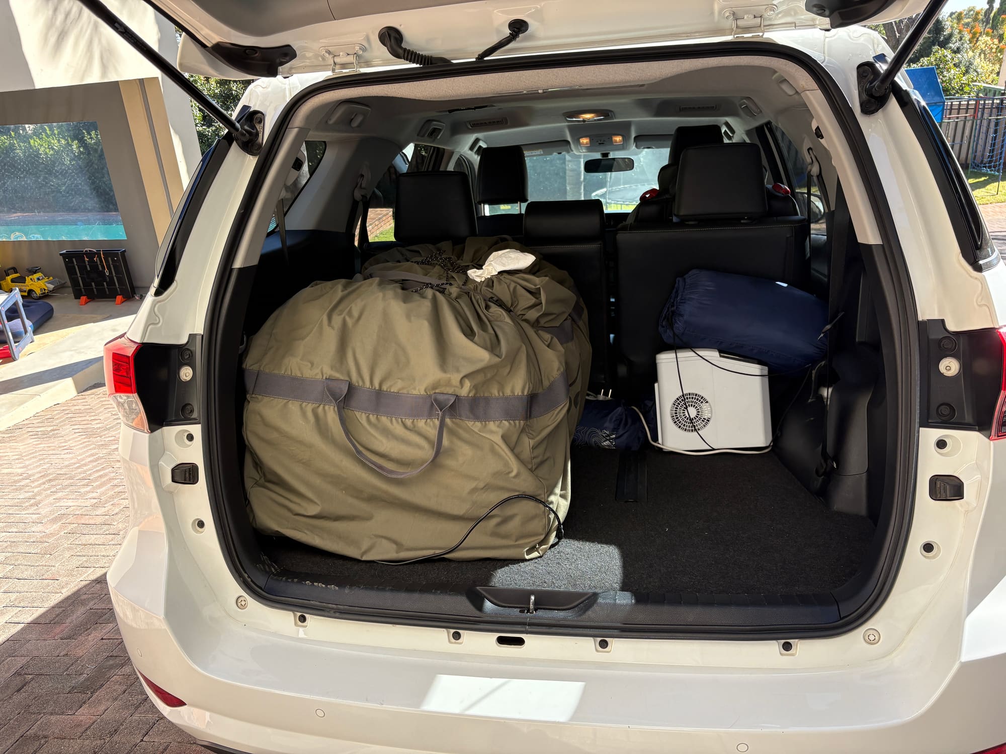 Car boot packed with the Coody Familia tent bag, cooler fridge, and bedding, ready to leave for Satara
