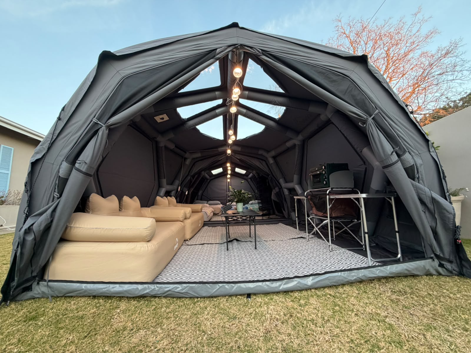 A Coody dome tent set up as a lounge with couch, coffee table and string lights in a garden in Cradock