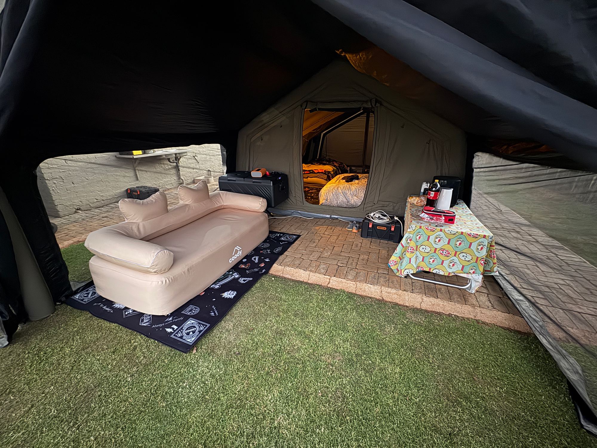 Lucy's Coody tent set up as a lounge with an inflatable sofa, cooler and snack table, bedroom visible through the doorway