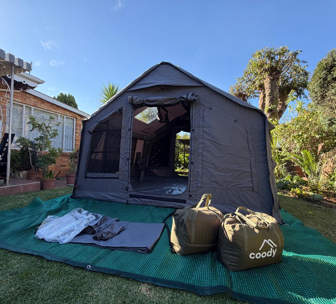Steve's grey Coody 8 set up in his backyard in Johannesburg, packed bags laid out on the groundsheet
